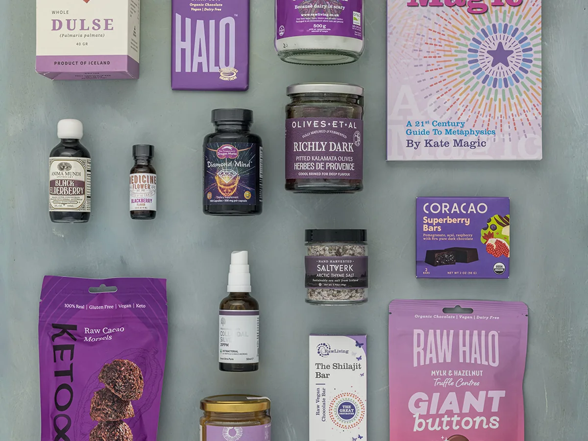A Raw Living purple flatlay of raw chocolate, dulse, coconut oil and the Actually Magic book by Kate Magic