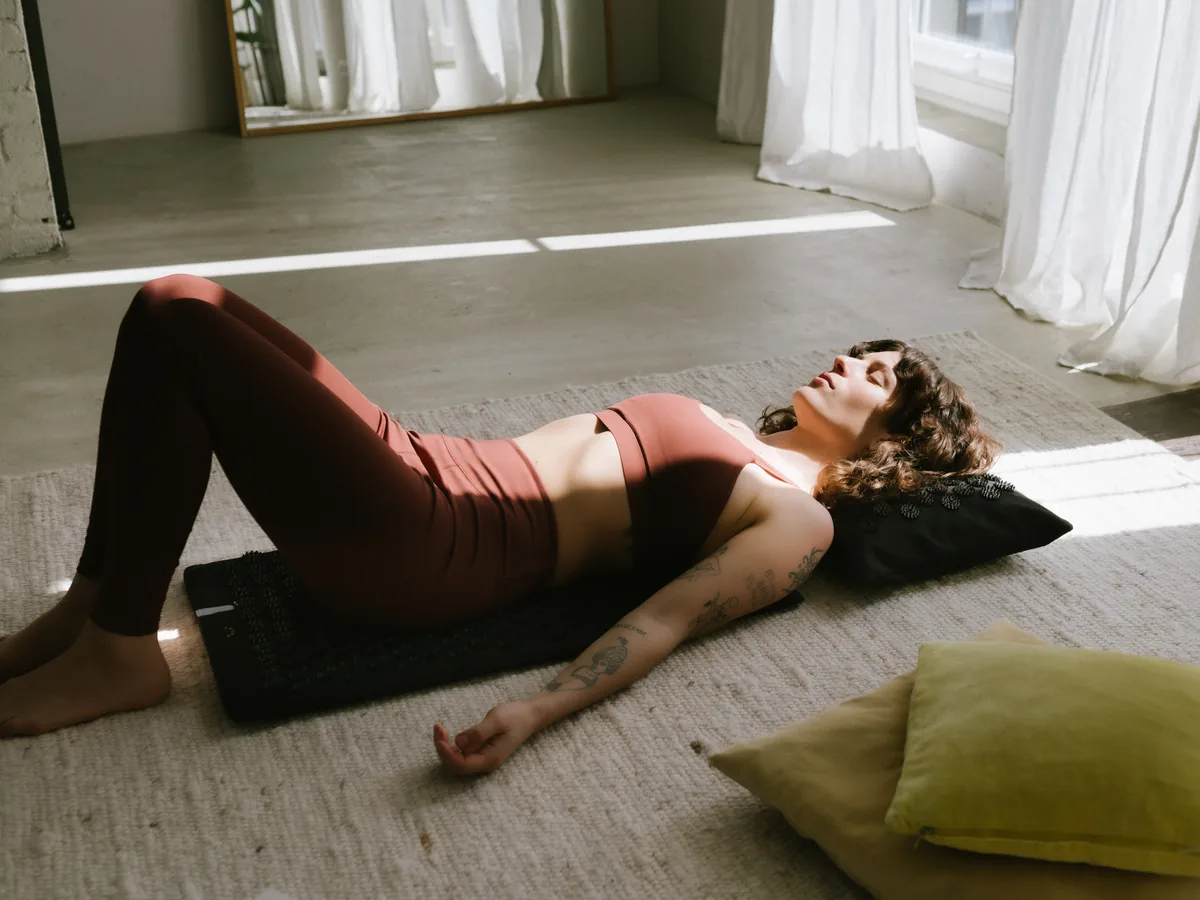 A teacher reclining on the Shakti premium acupressure mat and pillow set
