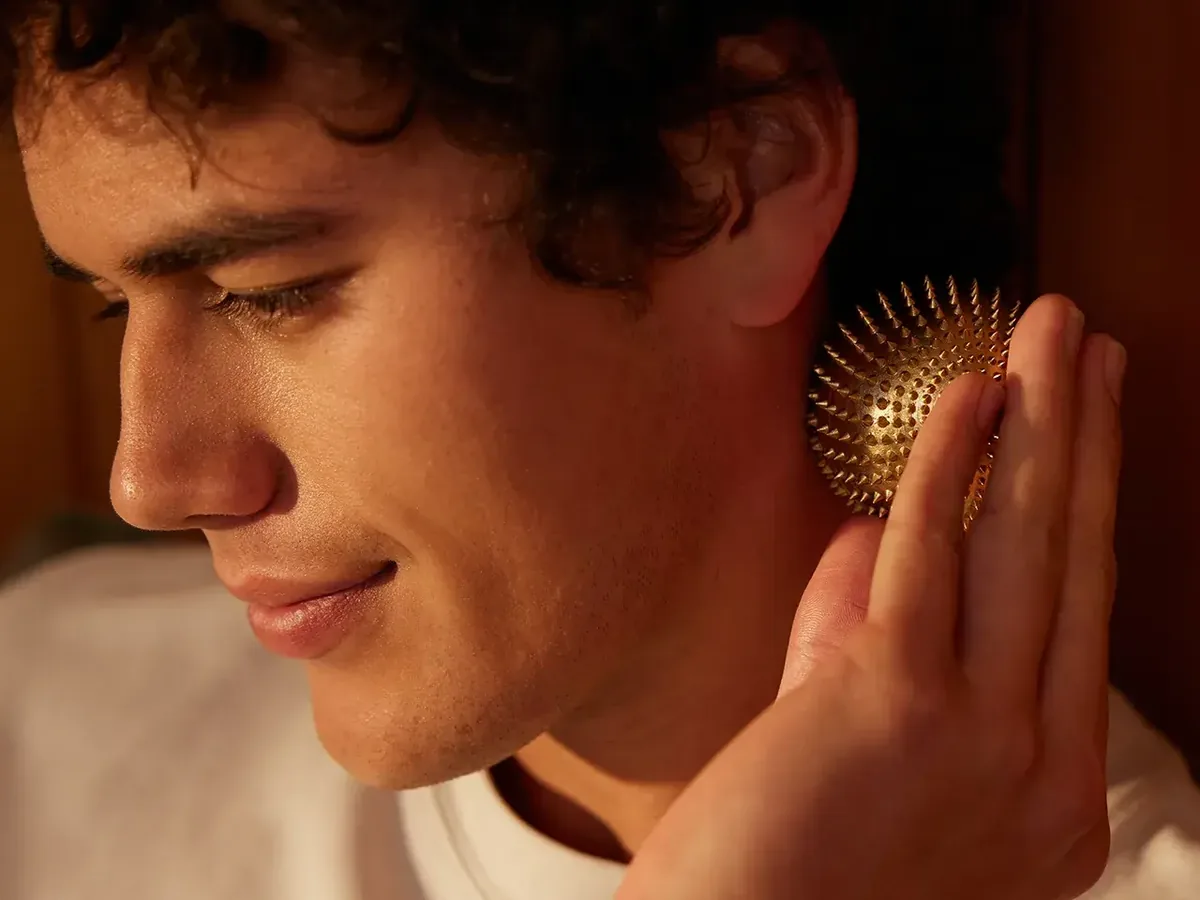The gold Shakti Wonderball rolled against the neck — kinetic acupressure massage tool